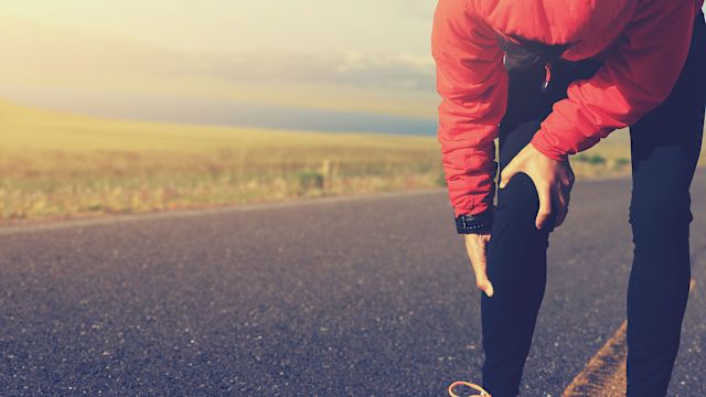 A woman out for a run stops to rub her knee. She knows she has knee arthritis risk factors. 