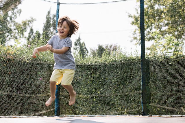 young boy jumping on outdoor yard trampoline