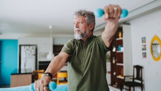 A senior man trains with hand weights as part of his physical rehabilitation program for treating CIDP.