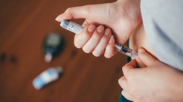 A woman with type 2 diabetes self-administers an injection of medication into her lower abdomen.