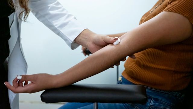 A healthcare provider draws blood from a female patient as part of a routine test to monitor how kidney disease is responding to treatment.