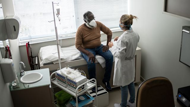 A senior man discusses the next steps in treatment for multiple myeloma with his oncologist in an exam room.