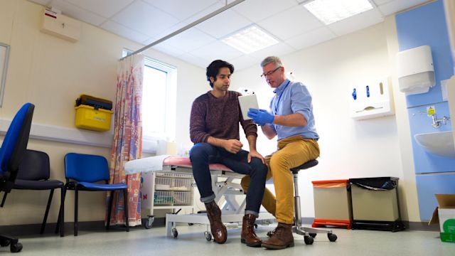 A young man with HCM discusses medications and exercise limitations with a cardiologist during an appointment.