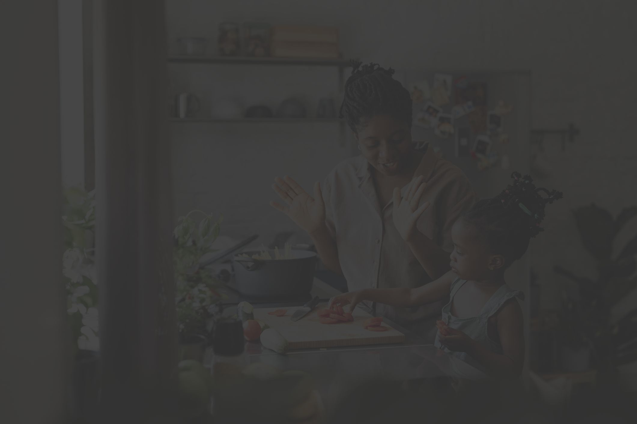 a young Black woman cooks healthy food in her kitchen with her daughter