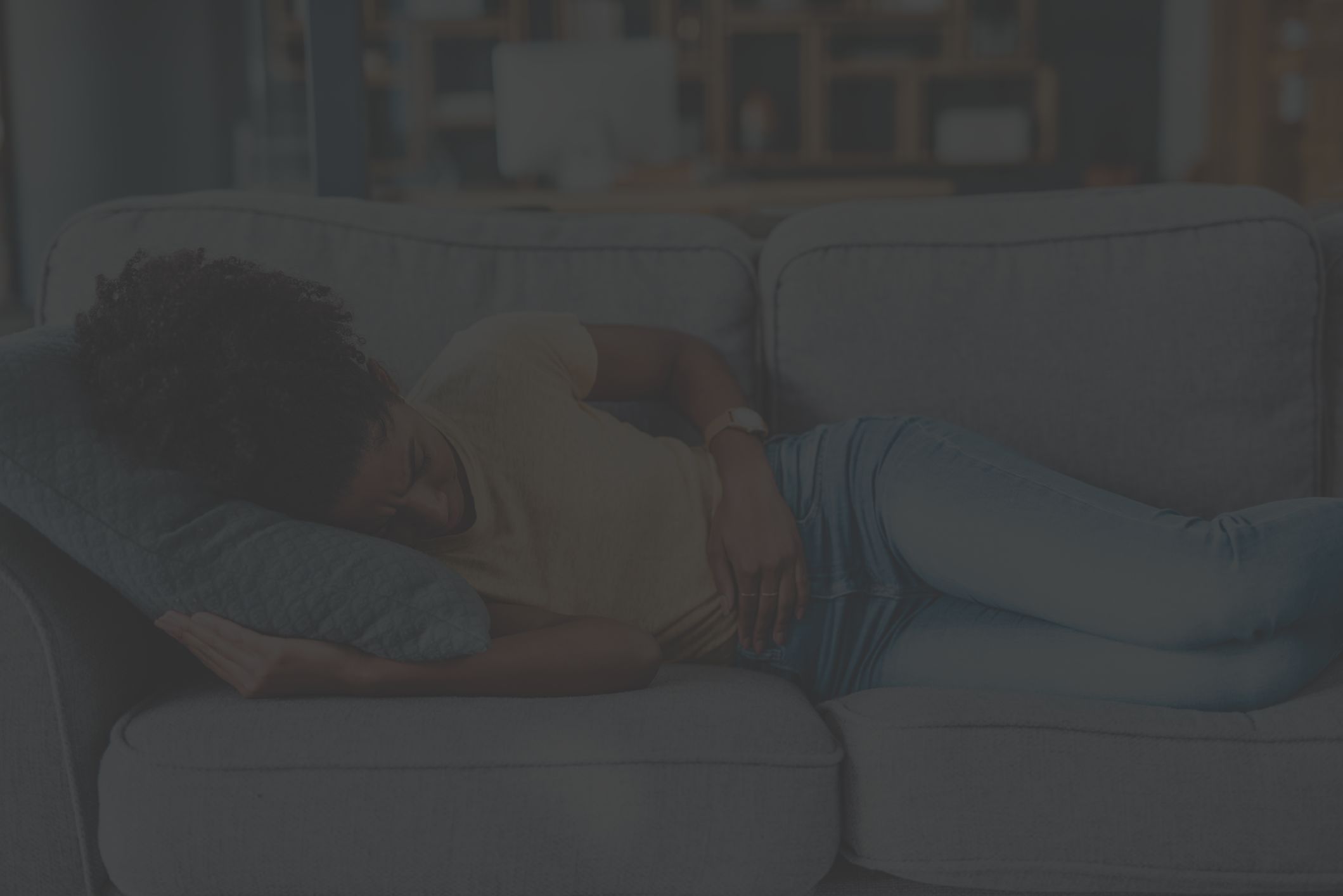 person clutching belly, lying on couch