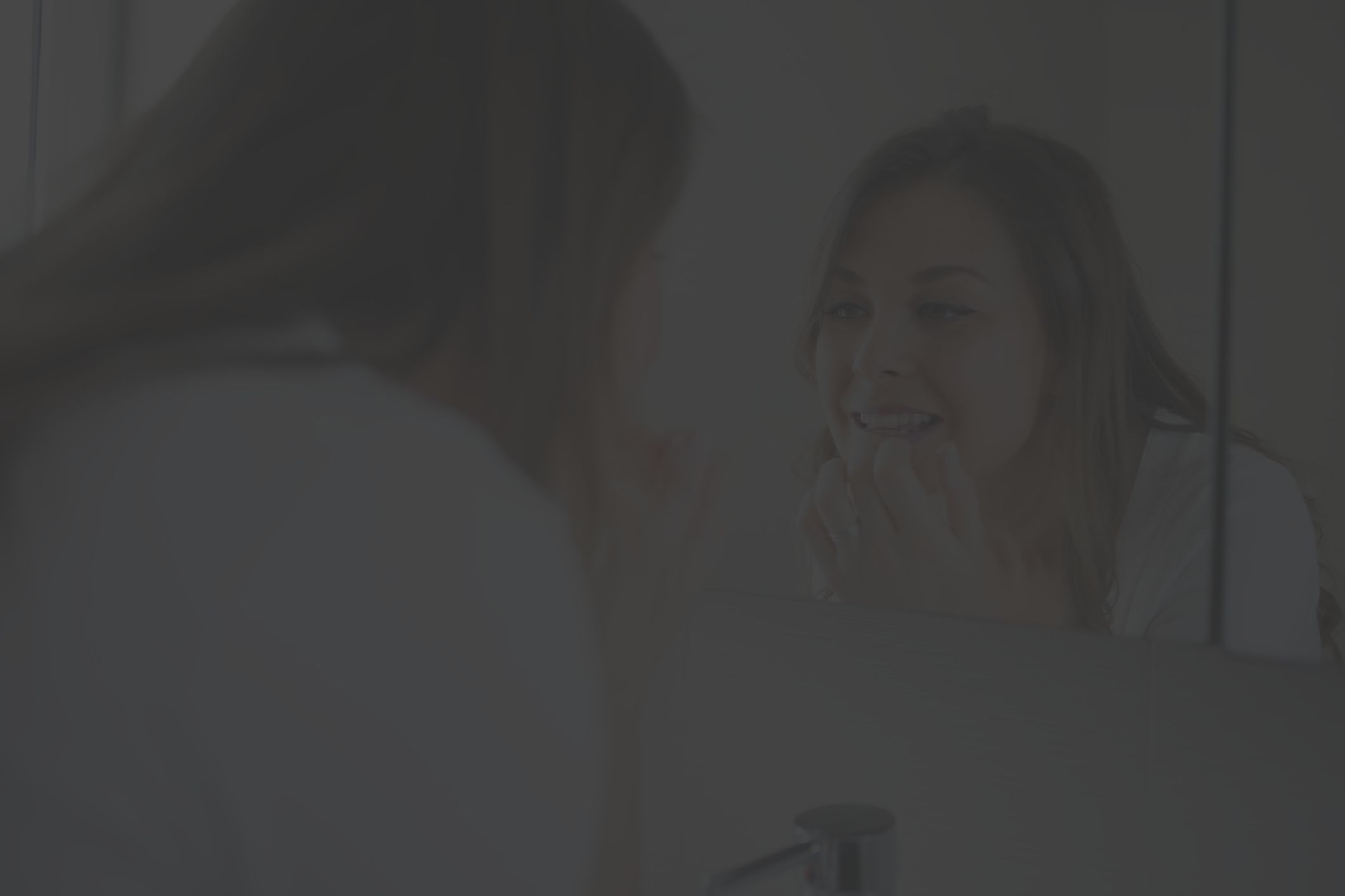 woman looking in the bathroom mirror at her teeth 