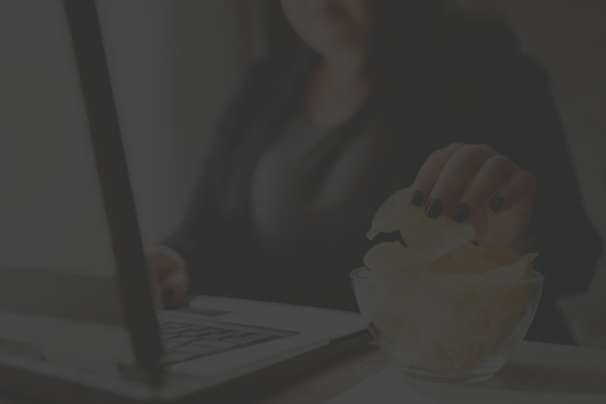 woman reaching for potato chips at her desk