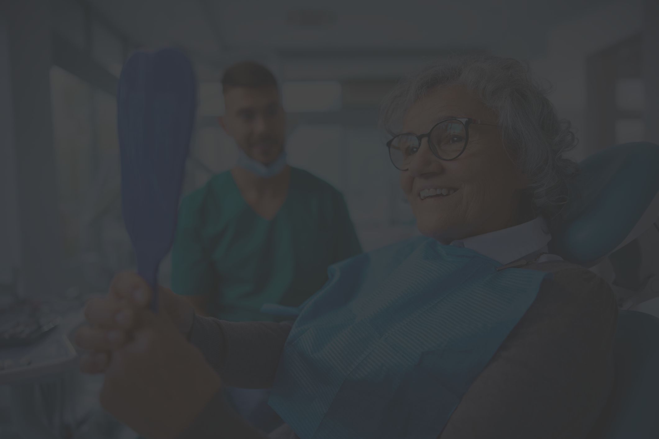 happy older woman in dentist chair looking in mirror