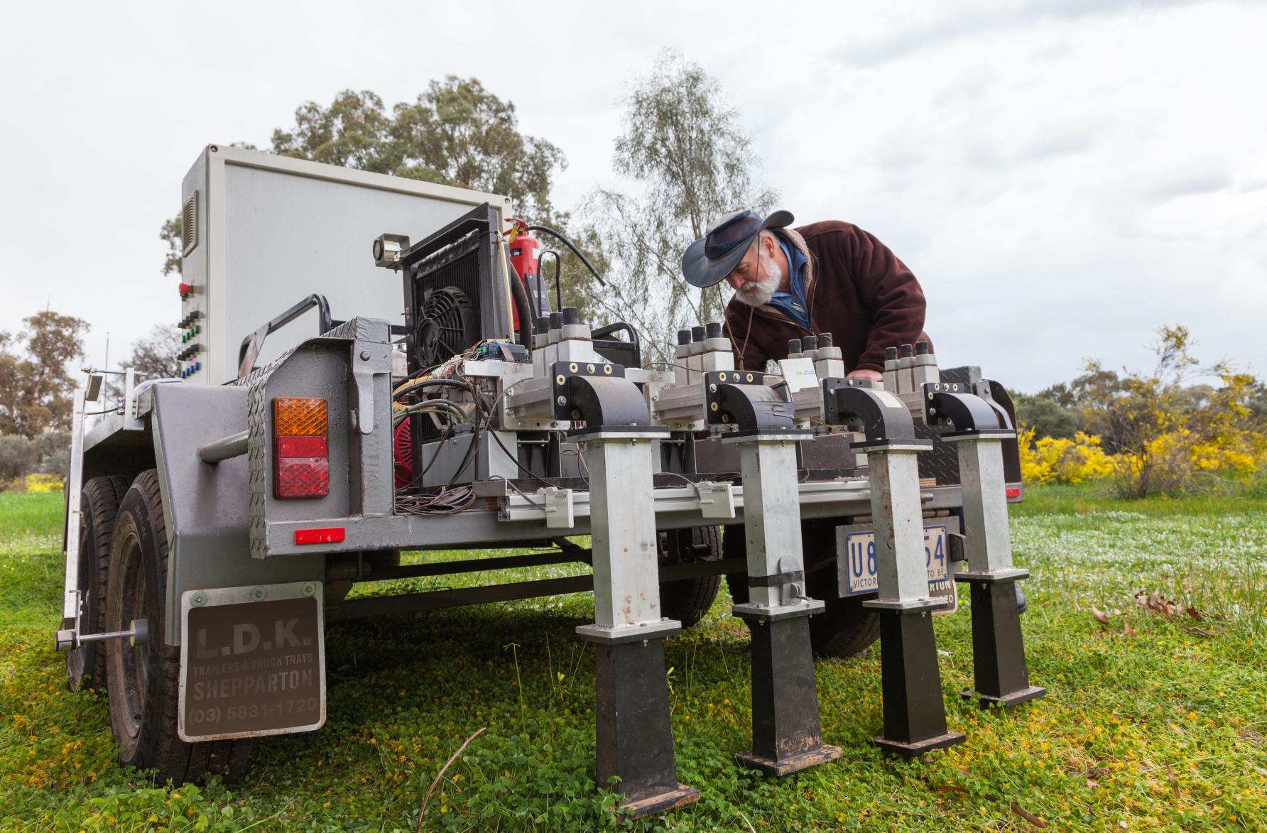 person leans over farming machinery