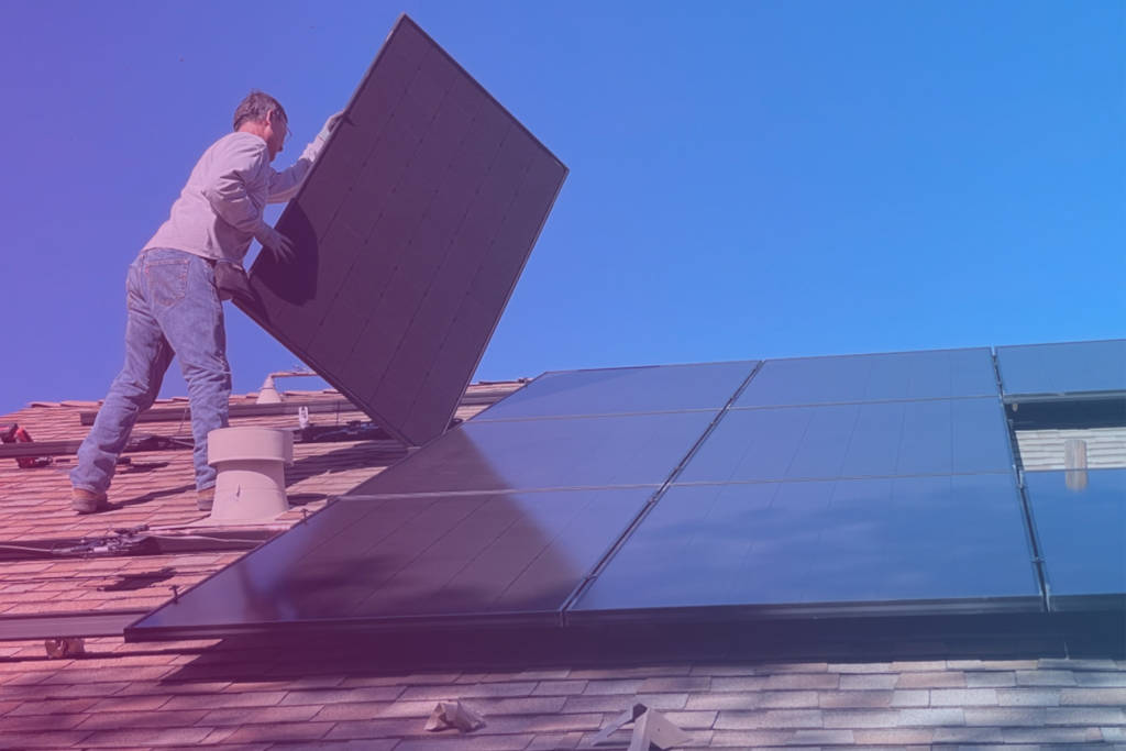 A worker install a solar panel on a rooftop.